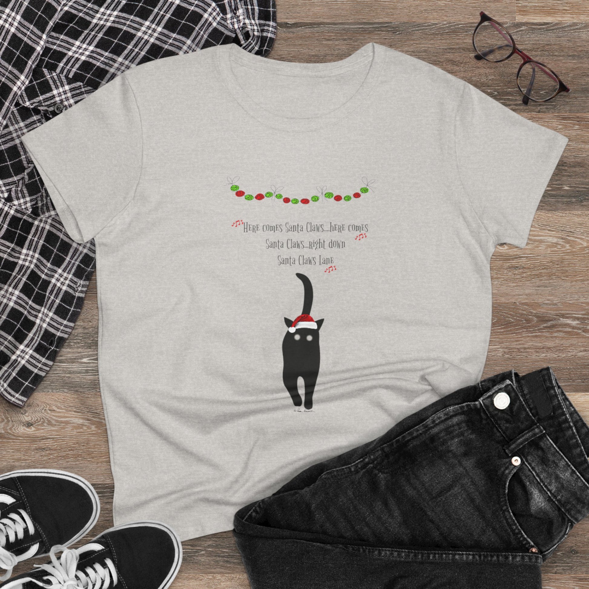 The Santa Claws T-shirt by Printify is a festive gray cotton top for women, featuring a black cat in a Santa hat with holiday lights and "Here comes Santa Claus" text—perfectly styled with jeans and sneakers for a cheerful holiday look.