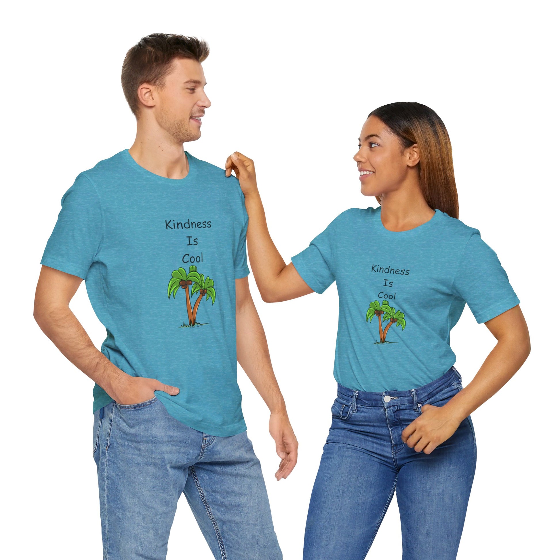 A man and a woman are standing together wearing matching Unisex Kindness-Is-Cool T-shirts from Printify, made of soft cotton jersey fabric by Bella+Canvas. The blue T-shirts feature the phrase "Kindness-Is-Cool" alongside an image of a palm tree. As the woman touches the man's shoulder, she smiles at him warmly.