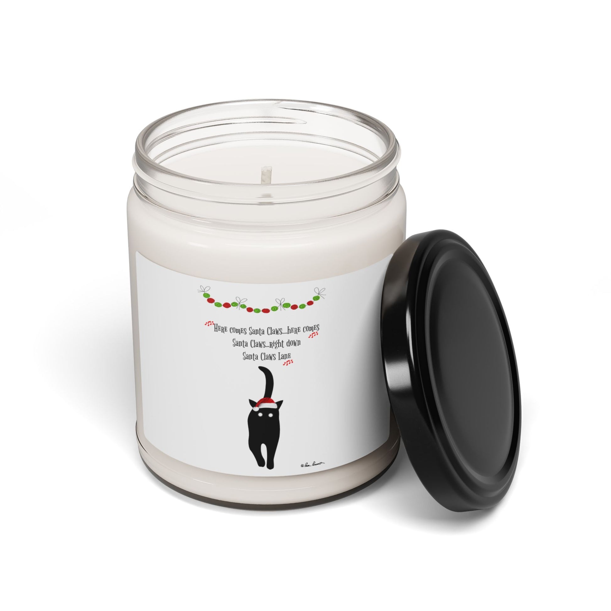 The Printify Festive-Cat Scented Soy Candle (9oz) features an eco-friendly white jar with a black lid, festive garland, a black cat in a Santa hat, and a holiday-themed message—ideal for holiday home decor.