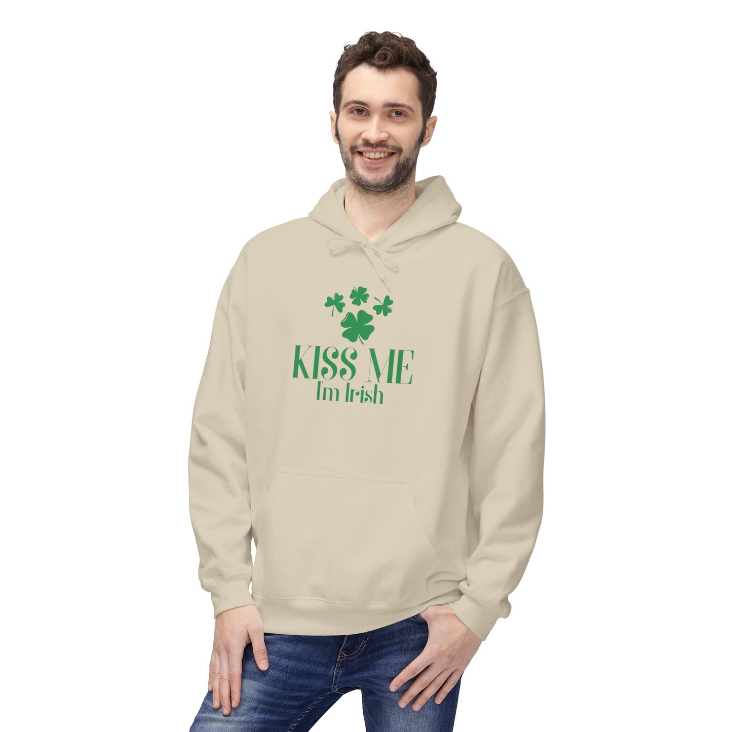 A man wearing the Printify "Kiss-Me I'm Irish Hoodie: St. Patricks Day Shamrock Pullover," featuring green text and shamrocks, stands smiling with one hand in his pocket.