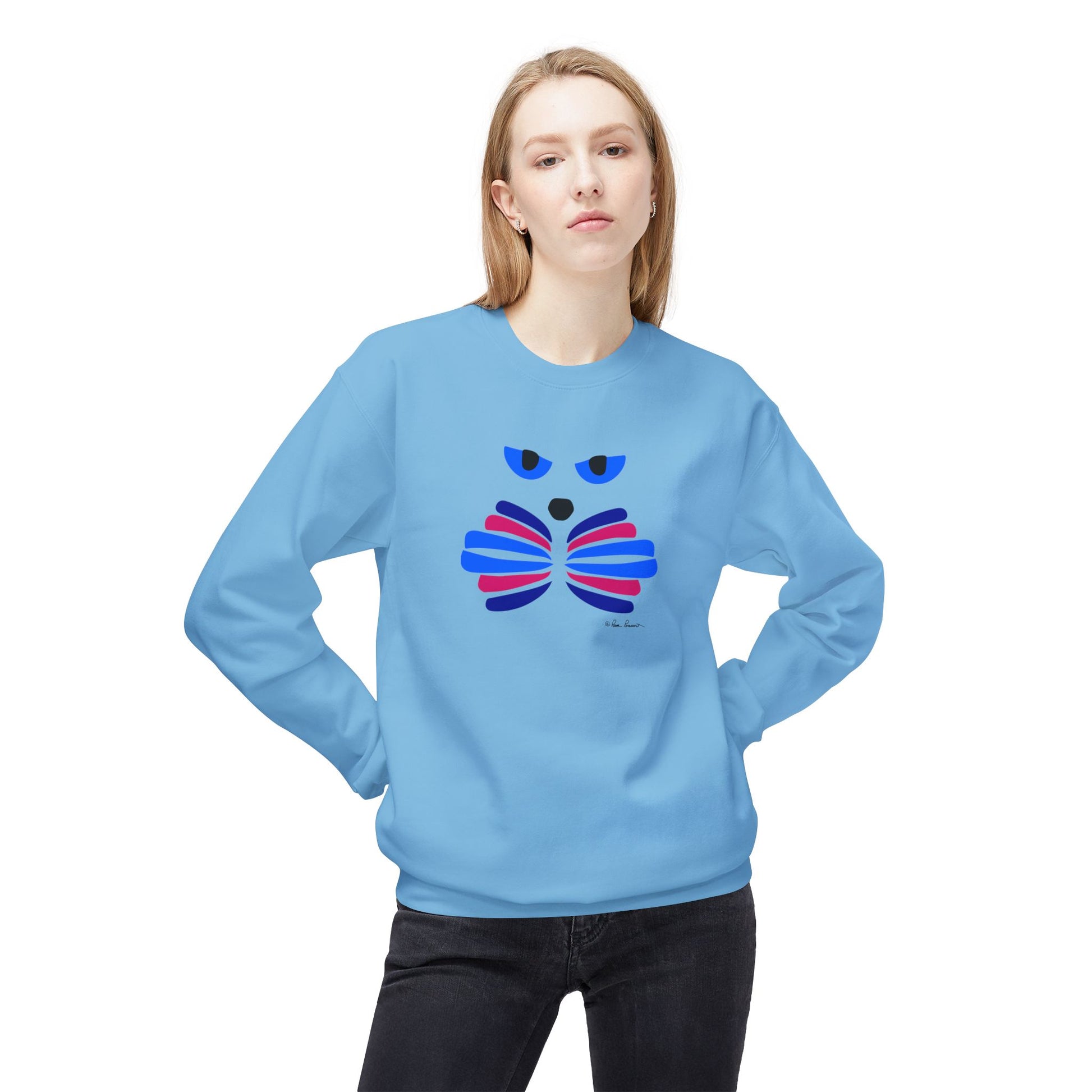 A woman stands with hands on hips, wearing the Printify Cat Face Crewneck Sweatshirt: Abstract Red & Blue Kitty, which features a cozy cotton blend and a stylized cat face design in red and blue tones.