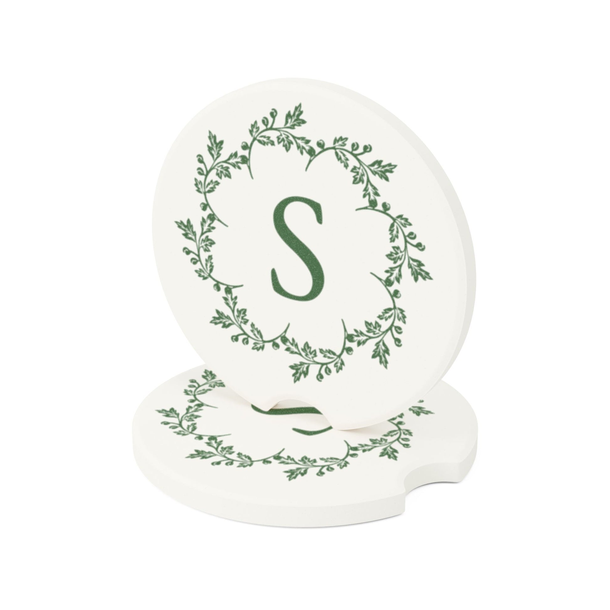 Add a touch of elegance to your vehicle with two white personalized car coasters from Printify, featuring an elegant green leaf design and a prominent letter "S" in the center. These absorbent coasters are made from natural soapstone, with one stylishly leaning against the other, making them both functional and charming car accessories.