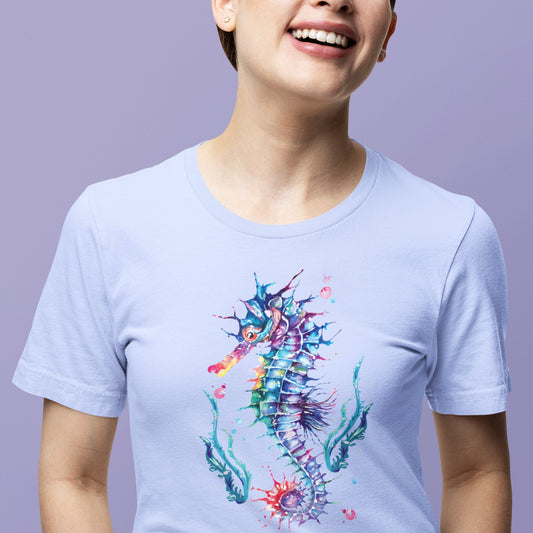 A person wearing a light blue Printify unisex t-shirt with a colorful seahorse design by Bella+Canvas smiles against a purple background.