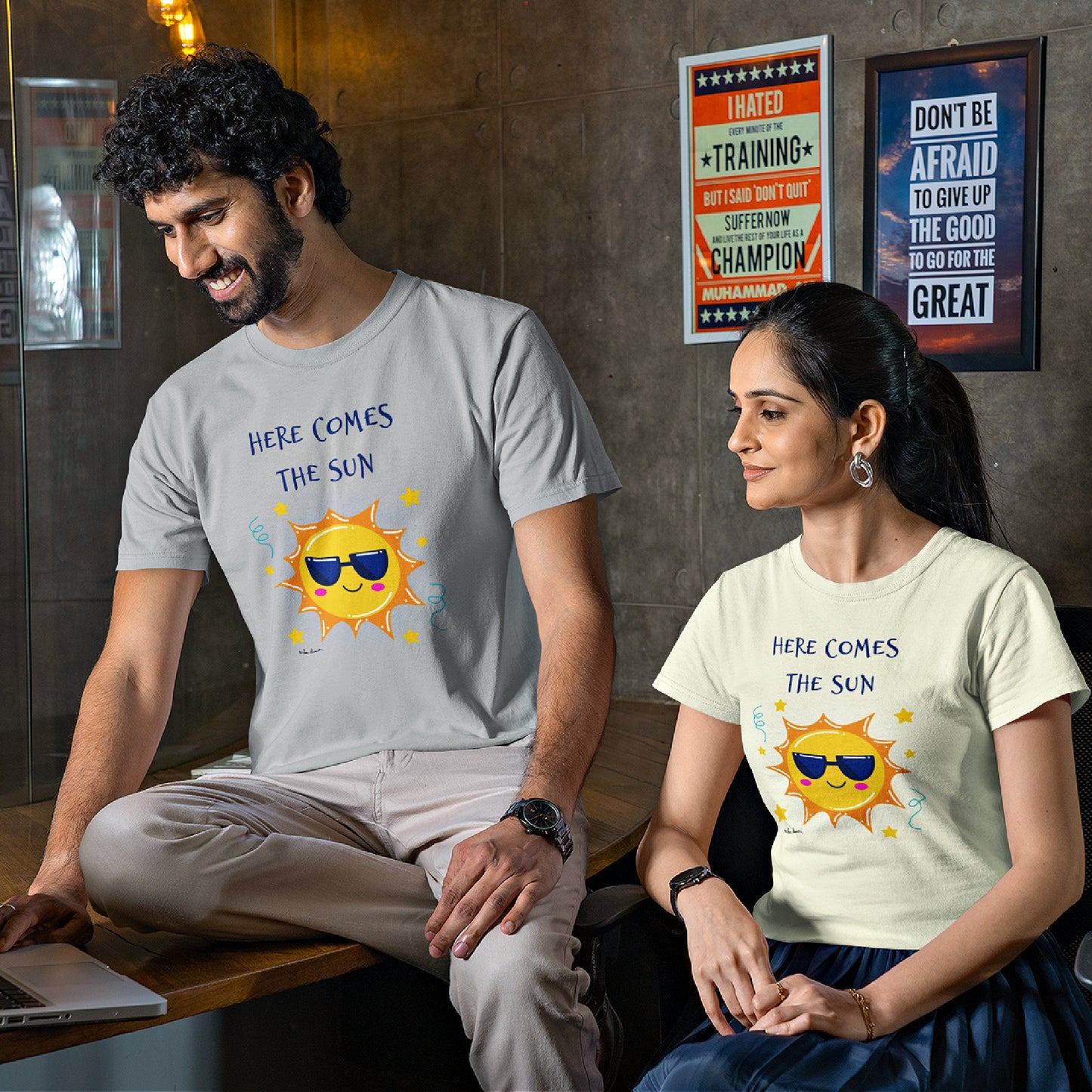 Mock up of two co-workers using a laptop computer; each wearing one of the t-shirts