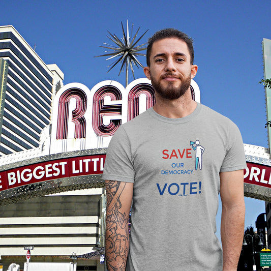 Mock up of a bearded man wearing our grey Unisex Get-Out-The-Vote T-shirt with the Reno Arch as a background