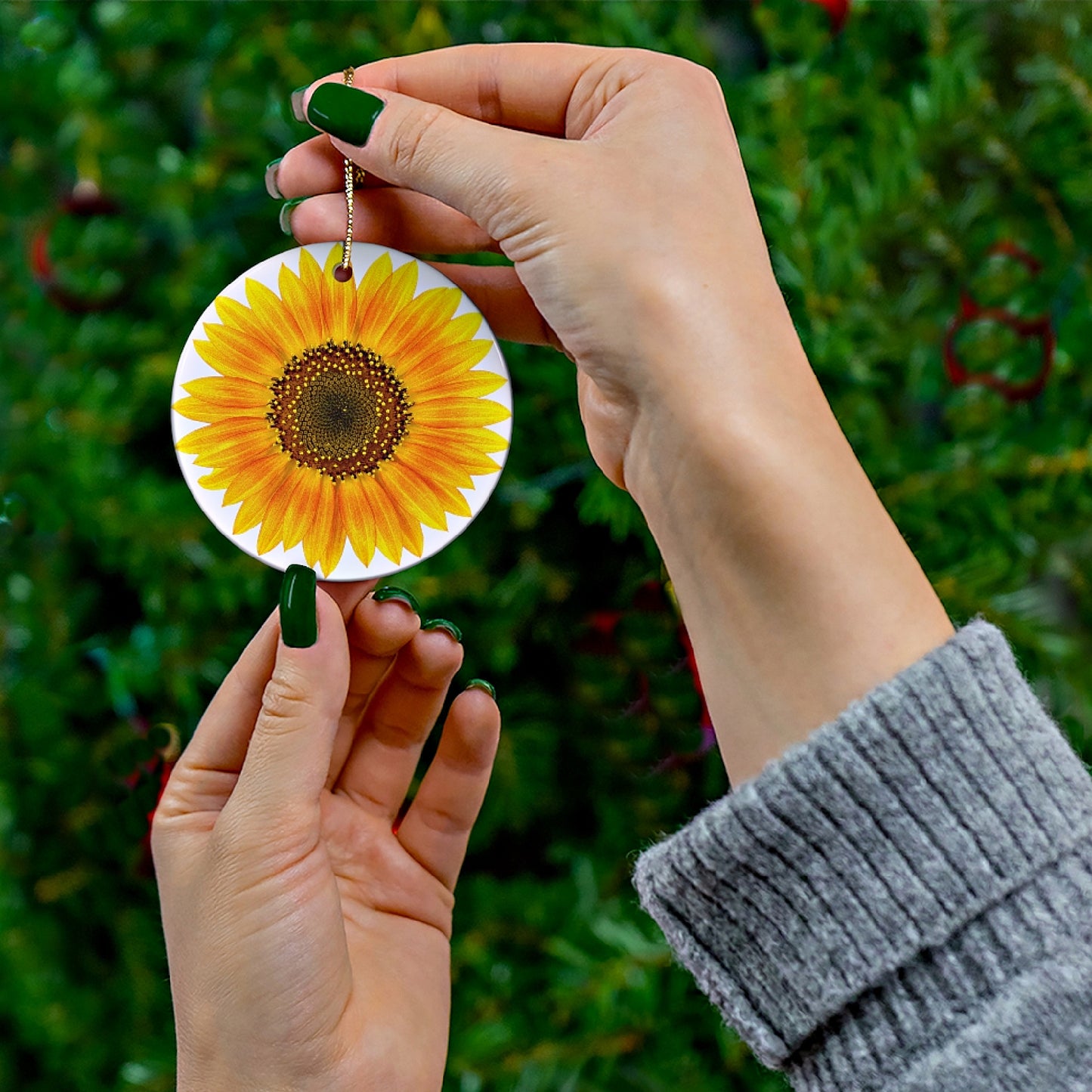 Mock up of our Sunflower Ceramic Ornament being held by a woman with green nail polish