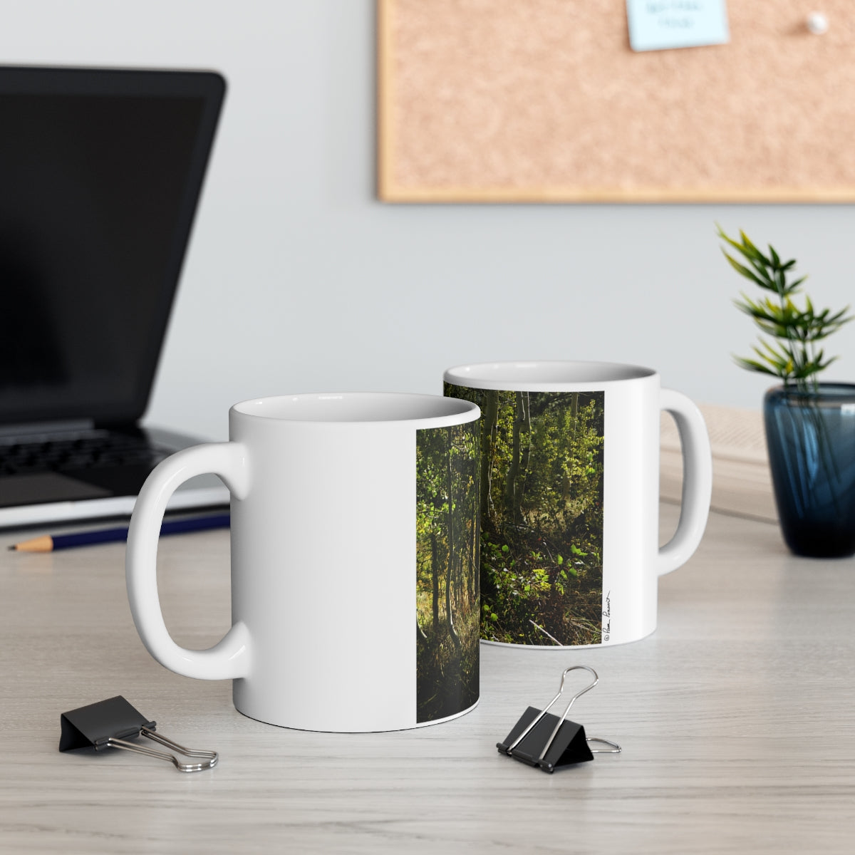 Mock up of 2 mugs on a surface with a computer laptop in the background