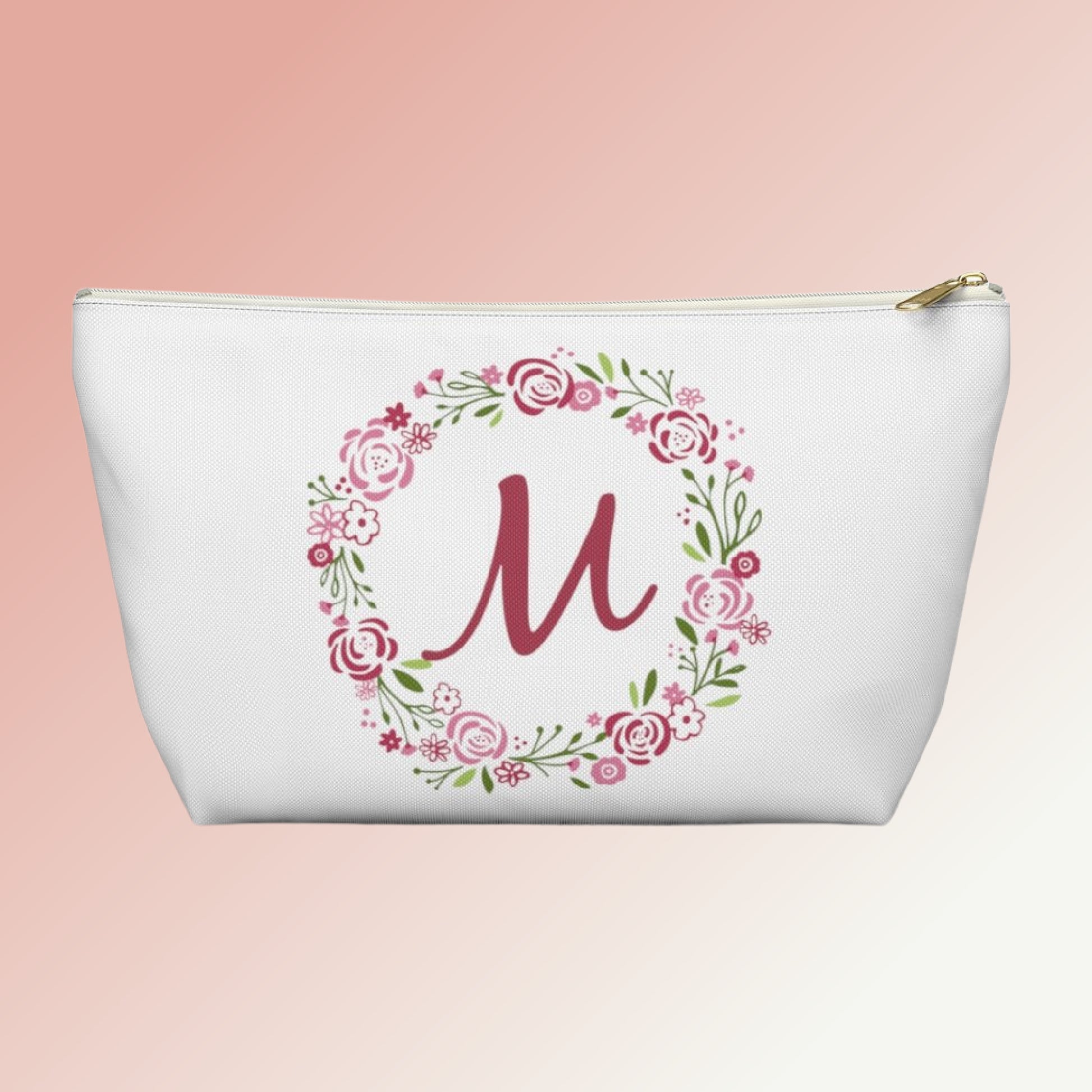 Photo of our customizable Accessory Pouch featuring the letter M inside of a pink and green floral wreath