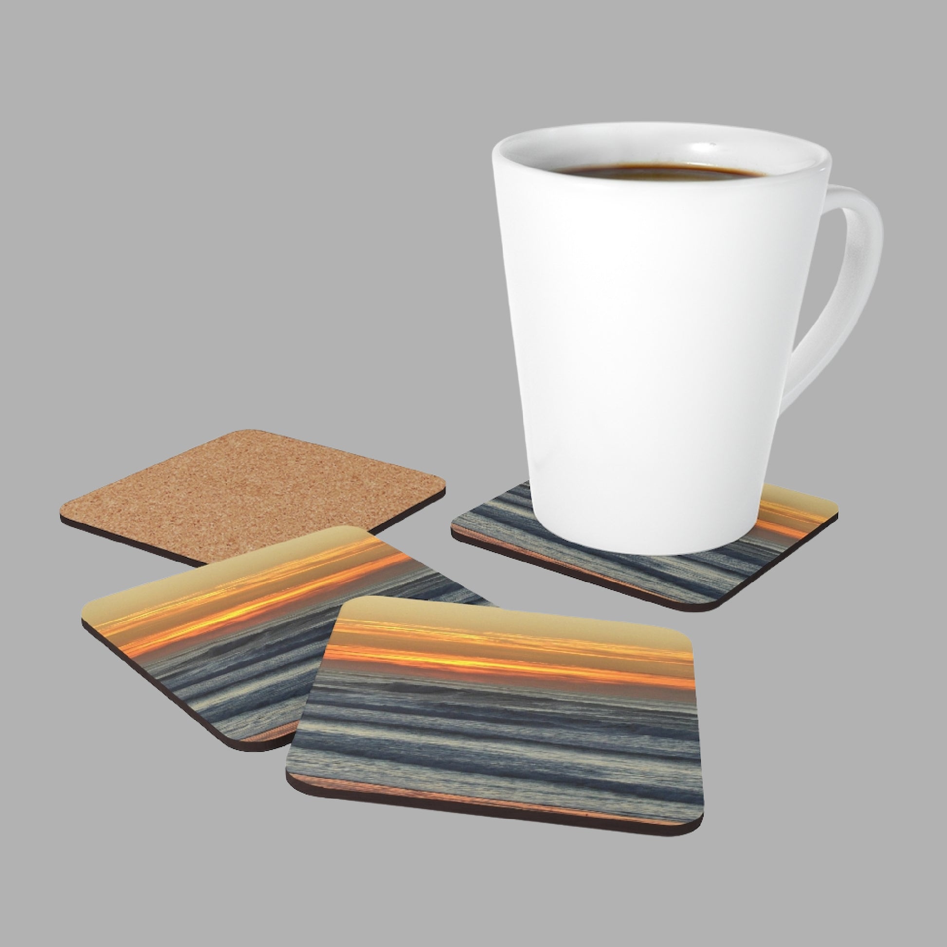 Mock up of a coffee mug on one of the Sunset-Seascape Coasters with the other 3 nearby