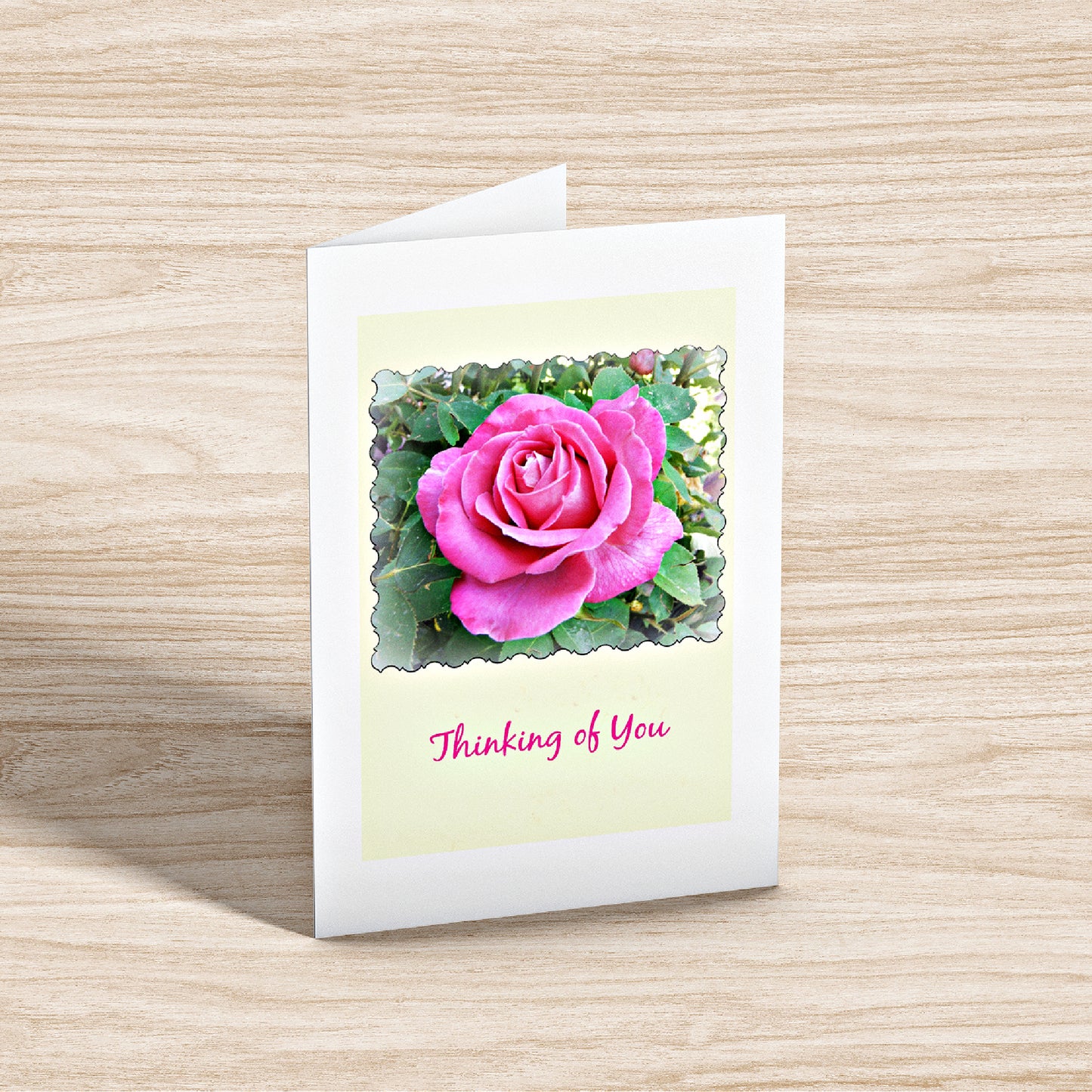 Mock up of our "Thinking of You" card standing on a wooden surface