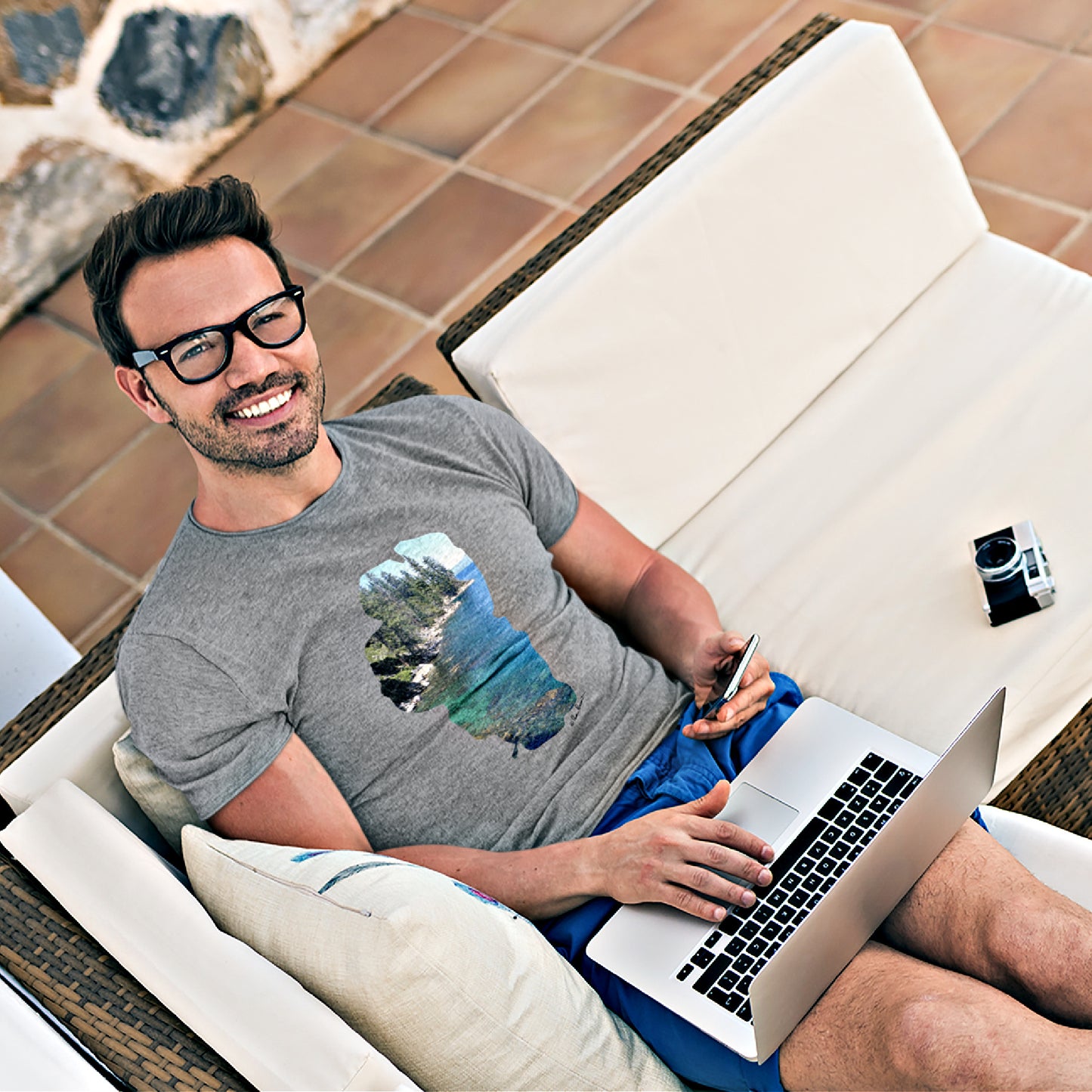 Mock up of a happy man working on his laptop computer while wearing our Sport Grey Unisex Lake-Tahoe T-shirt