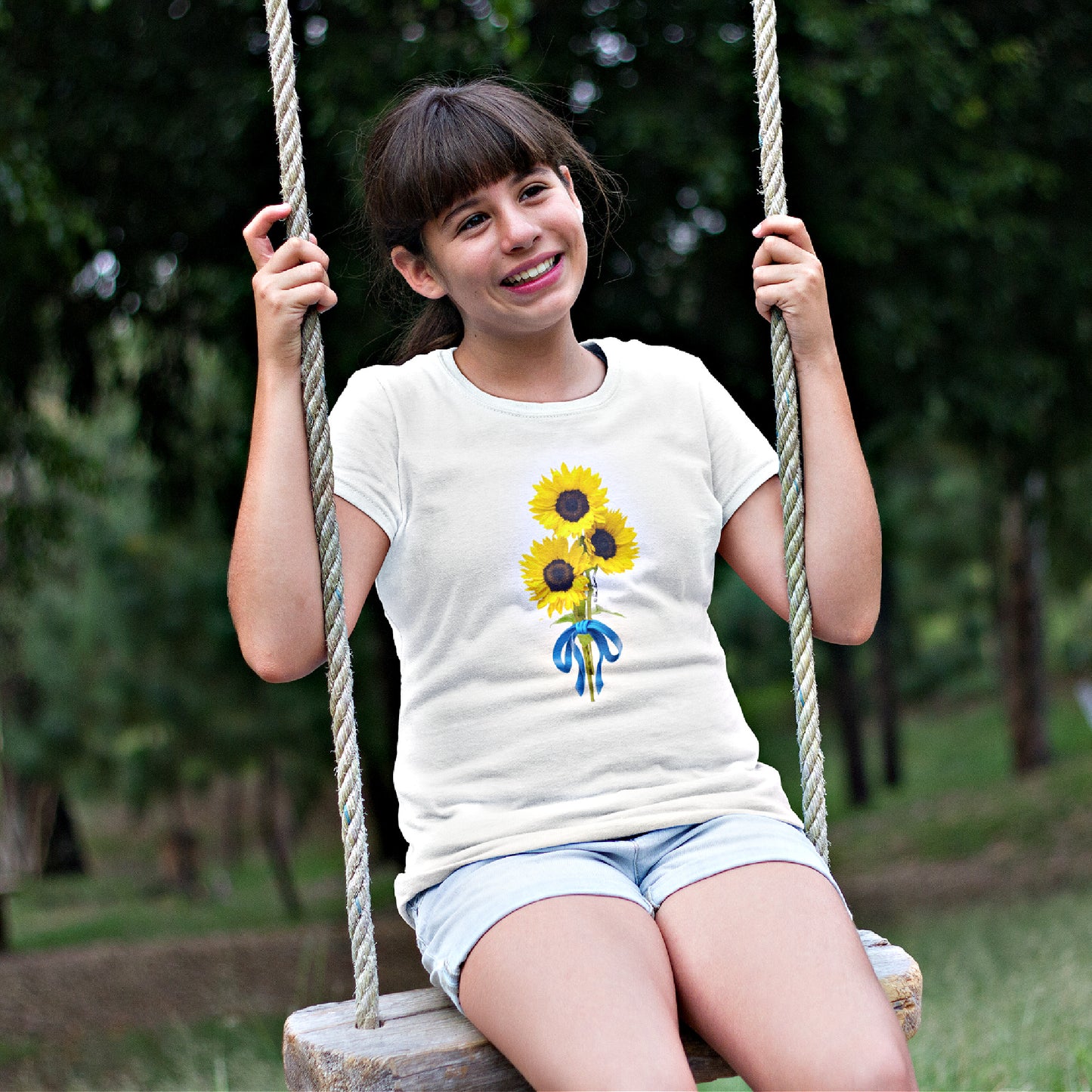 Mock up of a girl on a swing in a park wearing our white T-shirt