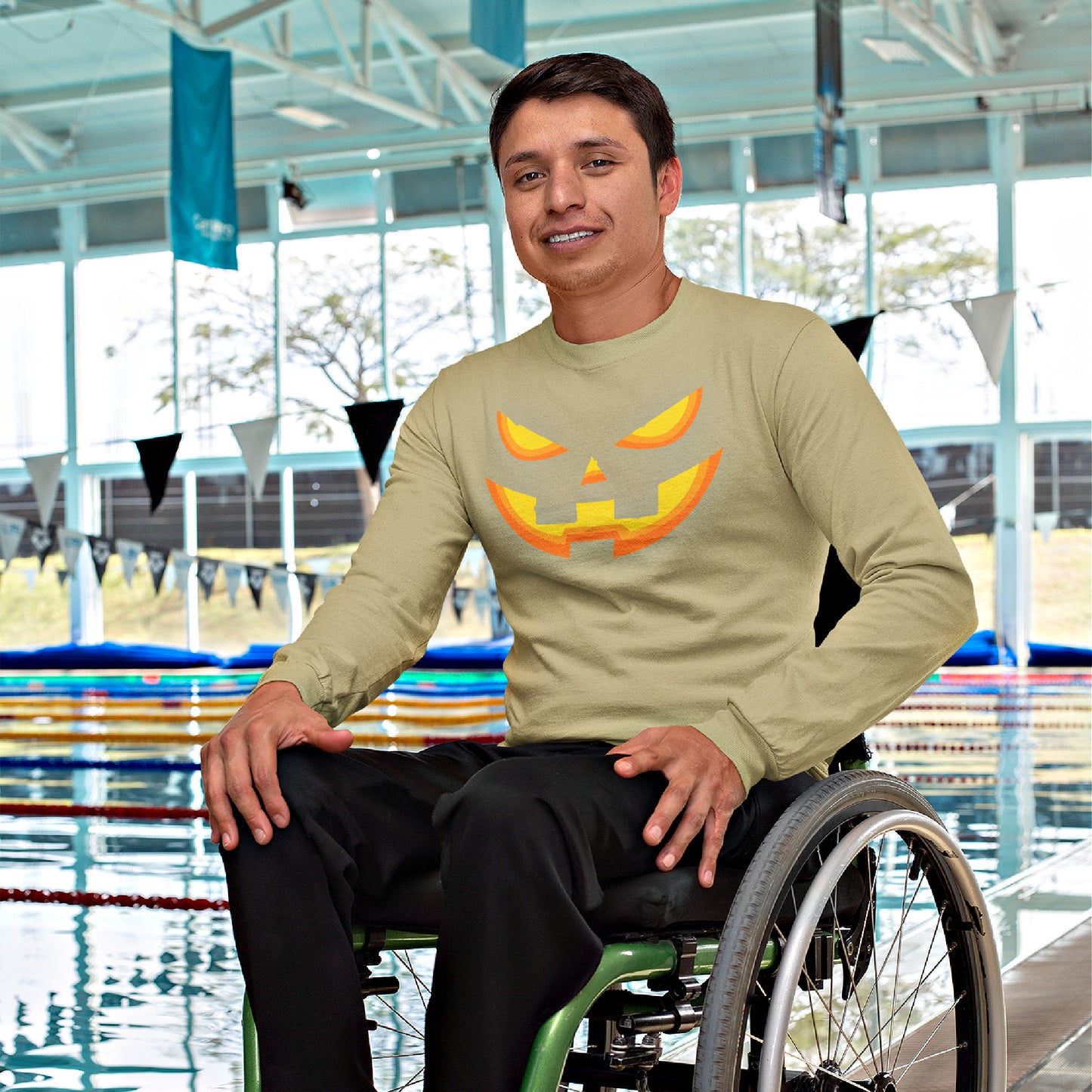 Mock up of a man sitting in a wheel-chair while wearing our Pumpkin-Face Halloween T-shirt