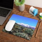 Mock up of our Nevada-Mountain Mouse pad on a surface next to a laptop computer