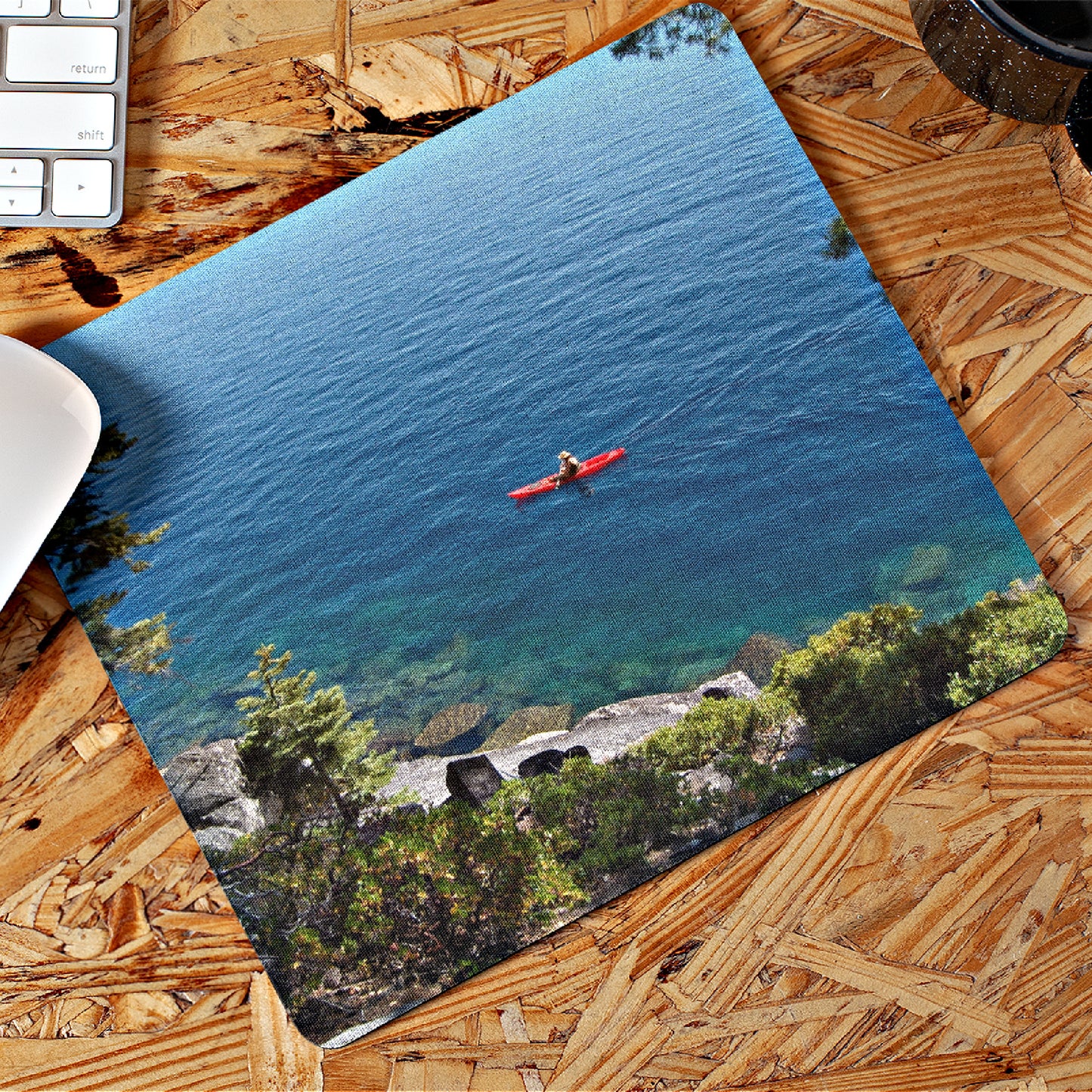 Mock up of our Kayaker Mouse Pad on a wooden surface