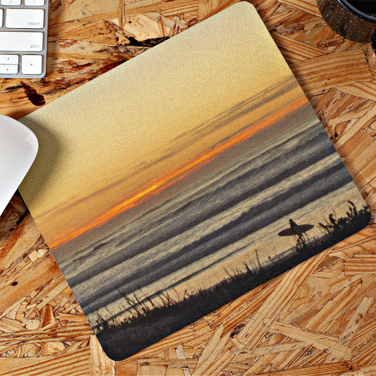 Mock up of our Mouse Pad with a Surfer at sunset lying on a wooden surface next to a mouse and a keyboard