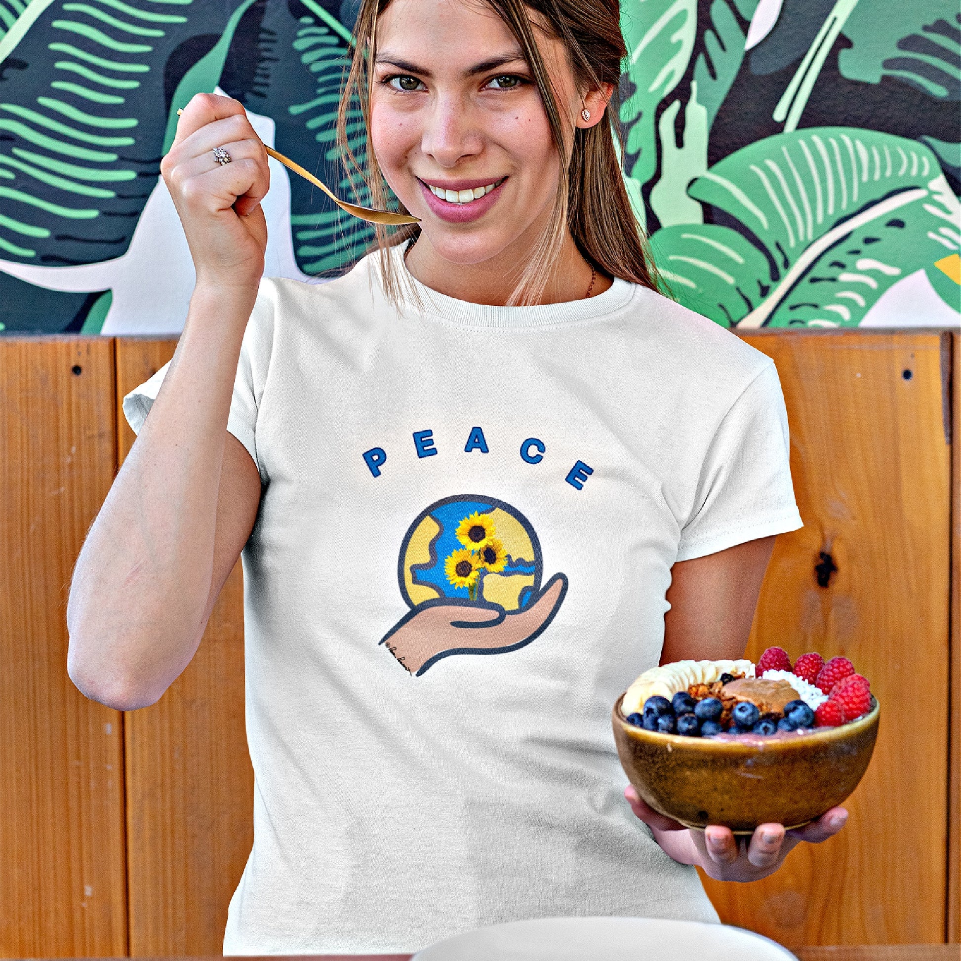 Mock up of a woman wearing our slim-fit t-shirt while eating a healthy fruit bowl