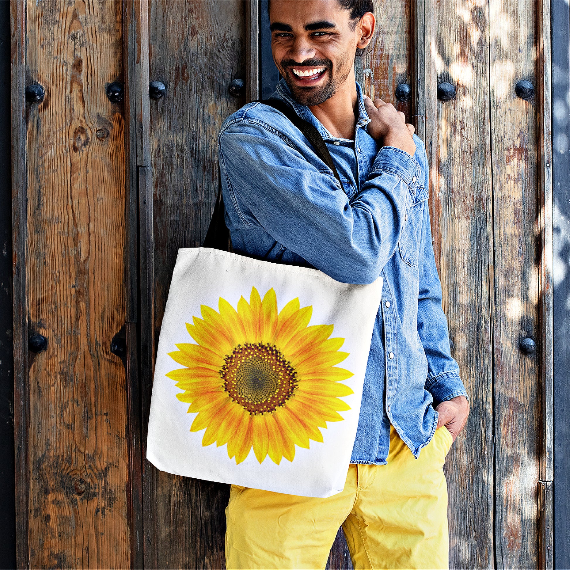 A mock up of a smiling man carrying our large Sunflower Tote Bag