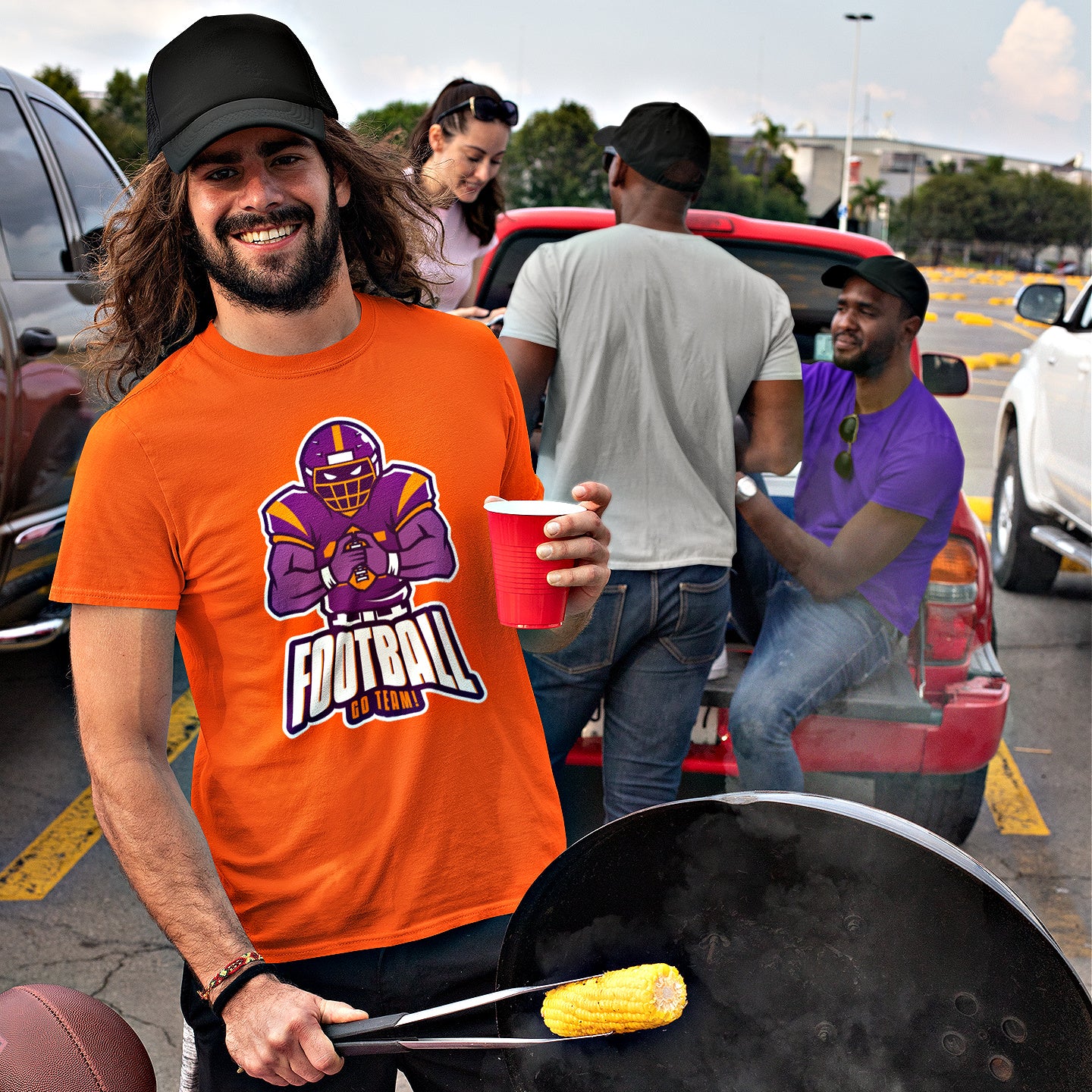 Mock up of a smiling man wearing our orange t-shirt at a tailgate party