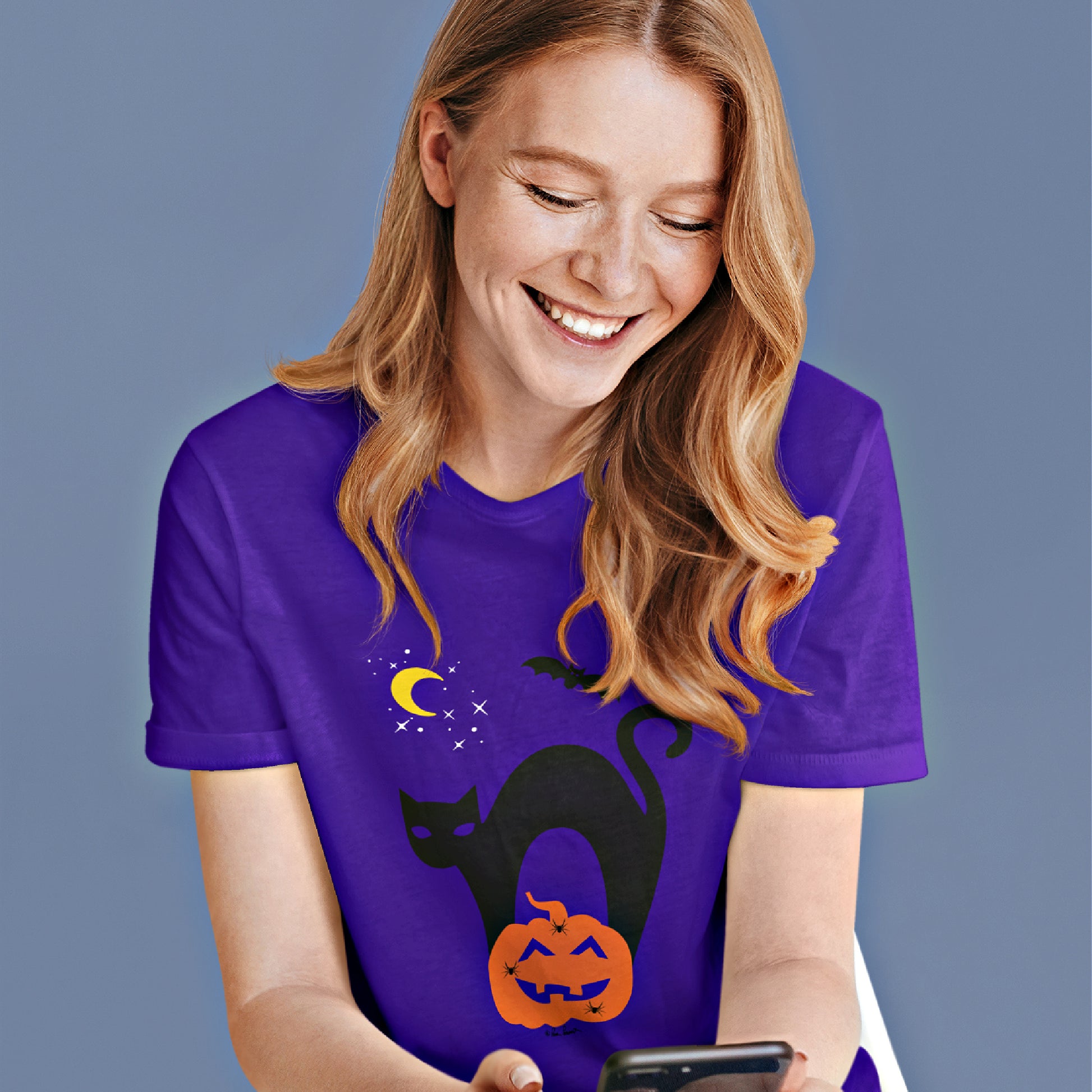 Mock up of a woman reading a message on her mobile phone while wearing our purple t-shirt